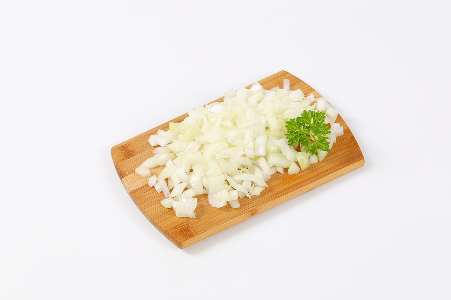 pile of chopped raw onion on wooden cutting board