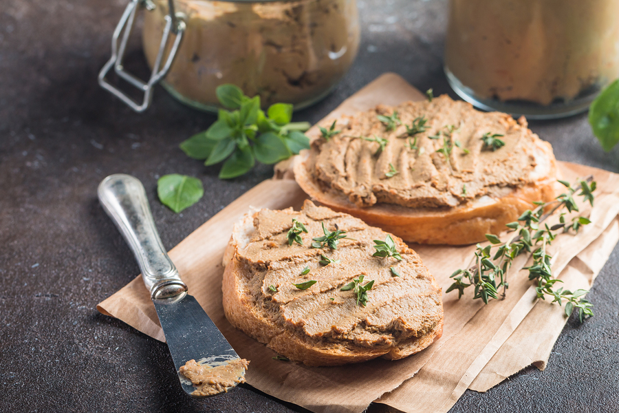 Fresh homemade chicken liver pate on bread over rustic background